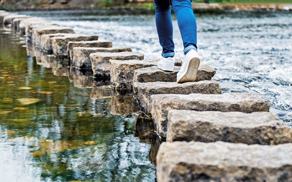 Woman crossing stepping stones on a river Woman crossing stepping stones on a river